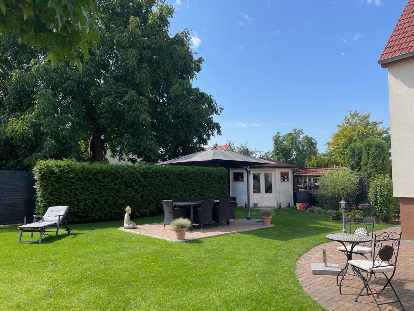 Nachher: Ein einladender Wohlfühlgarten mit klaren Linien, gemütlicher Sitzecke und frischem Grün. Nachher: Einladende Wohlfühloase